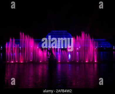 Ein Brunnen beleuchtet nach Magenta leuchtet vor der Palm House während der 2019 Kew Weihnachten Licht Anzeige an den Kew Gardens, London, UK Stockfoto