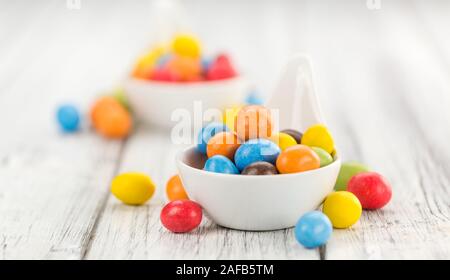 Cocolate beschichtet Erdnüsse auf rustikalen Holzmöbeln Hintergrund (Nahaufnahme) Stockfoto