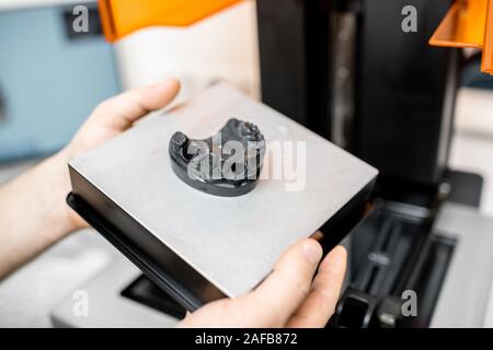 Zahntechniker entfernen Spannbacken aus dem 3D-Drucker im Labor, Modellierung Rahmen für die Produktion Implantat Stockfoto