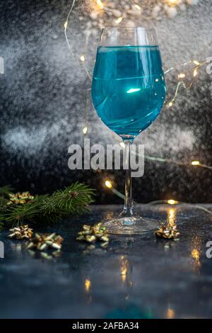 Blau Wein in ein Glas auf einem dunklen Hintergrund. Im Hintergrund bokeh der Lichter. Festliche Stimmung. Stockfoto