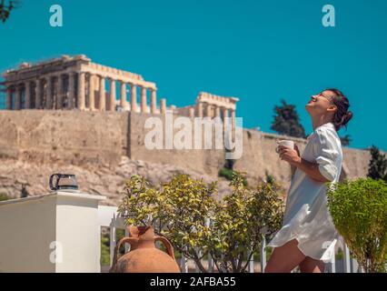 Junge Frau touristische Frühstücken auf Haus Balkon, mit Blick auf den Parthenon in Athen Akropolis, Griechenland Stockfoto