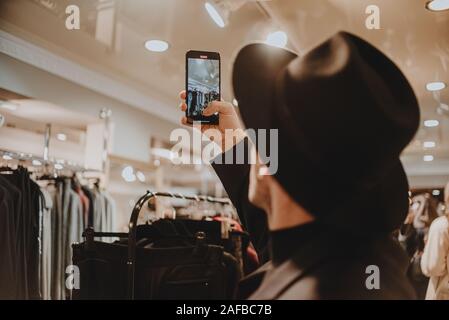 Junger Mann in einem schwarzen Hut macht Fotos auf dem Telefon Stockfoto