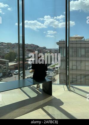 Blick auf eine Frau auf einer Bank am neu eröffneten Museum für moderne Kunst in Istanbul sitzen. Dolapdere Fläche von Istanbul und bewölkter Himmel sind auf der Rückseite Stockfoto