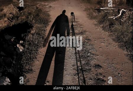 Selbstporträt mit Kameraständer am späten Abend. Konzentrieren Sie sich auf den Schatten des Fotografen. Stockfoto