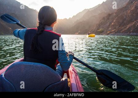 Frau Kajak im malerischen Hatta See in Dubai bei Sonnenuntergang Stockfoto