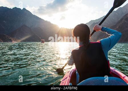 Frau Kajak im malerischen Hatta See in Dubai bei Sonnenuntergang Stockfoto