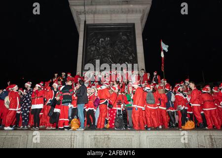 Trafalgar Square, London, Großbritannien. Dezember 2019. Während des jährlichen Santacon-Events im Jahr 2019 versammelt sich eine große Gruppe von Teilnehmern in Weihnachtsmannskostümen am Trafalgar Square in London. Die nächtliche Szene zeigt festliche rote Outfits, Hüte und Requisiten, während die Nachtschwärmer vor den berühmten Denkmälern und Skulpturen des Platzes feiern. Das Bild fängt den verspielten Geist, die gemeinsame Energie und die saisonale Stimmung dieses kostümierten öffentlichen Treffens im Herzen der Stadt ein. Penelope Barritt/Alamy Live News Stockfoto