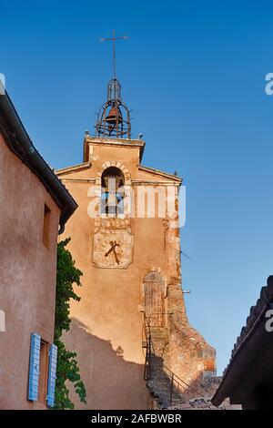 Der Glockenturm der Hauptkirche in Roussillon hat eine Uhr und einen ungewöhnlichen Eintrag Tür in der Nähe der Spitze des Turms. Stockfoto