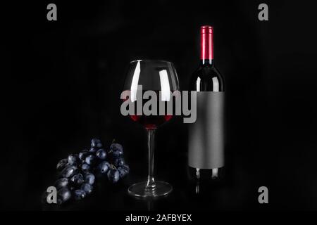 Wein Glas Rotwein und Flasche, Weintraube auf schwarzem Hintergrund. Stockfoto