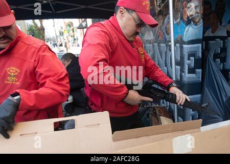 San Francisco, Ca, USA. 14 Dez, 2019. Ein San Francisco Police Officer ist Kontrolle ein AR-15 style Gewehr in von Menschen gehandelt während der jährlichen Gewehr kaufen - Zurück Veranstaltung von United Playaz in San Francisco, Kalifornien, USA am Dezember 14, 2019 gehostet wird. Heute ist der 7. Jahrestag der Sandy Hook Massenerschießungen. Credit: Sipa USA/Alamy leben Nachrichten Stockfoto
