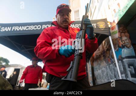 San Francisco, Ca, USA. 14 Dez, 2019. Ein San Francisco Police Officer ist Kontrolle ein AR-15 style Gewehr in von Menschen gehandelt während der jährlichen Gewehr kaufen - Zurück Veranstaltung von United Playaz in San Francisco, Kalifornien, USA am Dezember 14, 2019 gehostet wird. Heute ist der 7. Jahrestag der Sandy Hook Massenerschießungen. Credit: Sipa USA/Alamy leben Nachrichten Stockfoto