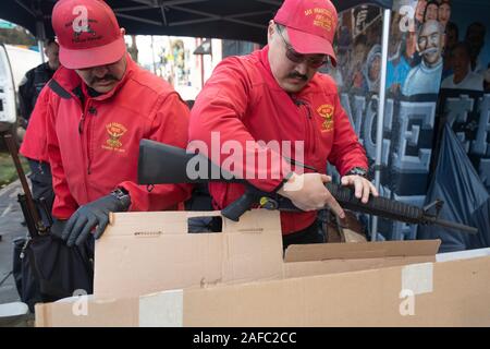 San Francisco, Ca, USA. 14 Dez, 2019. Ein San Francisco Police Officer ist Kontrolle ein AR-15 style Gewehr in von Menschen gehandelt während der jährlichen Gewehr kaufen - Zurück Veranstaltung von United Playaz in San Francisco, Kalifornien, USA am Dezember 14, 2019 gehostet wird. Heute ist der 7. Jahrestag der Sandy Hook Massenerschießungen. Credit: Sipa USA/Alamy leben Nachrichten Stockfoto