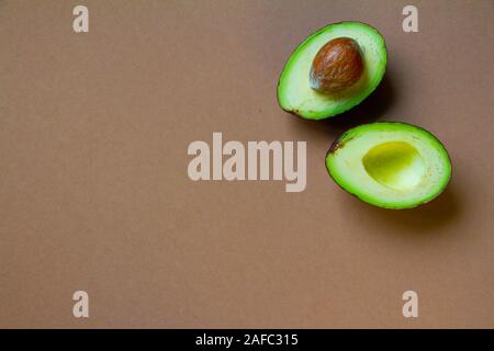 Die beiden Hälften des raw Avocado auf braunem Hintergrund, kreative Essen Konzept Stockfoto