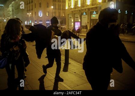 Beirut, Libanon. 14 Dez, 2019. Eine Demonstrantin trägt eine verletzte Frau bei Zusammenstößen mit der libanesischen Polizei in der Nähe der libanesischen Parlament Gebäude. Credit: Marwan Naamani/dpa/Alamy leben Nachrichten Stockfoto