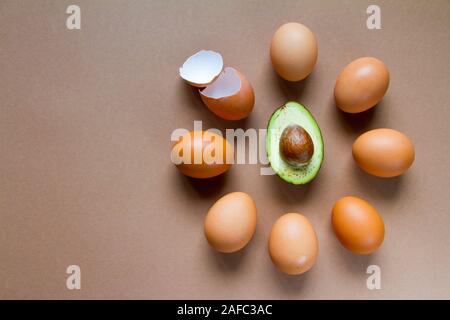 Ein paar braune Hühnereier und eierschalenfarbenen rund die Hälfte der reife Avocado, das Konzept der ketogenic Ernährung, das Image der Zifferblatt Stockfoto