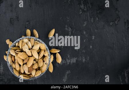 Teil der gerösteten Mandeln (in der Shell) auf dunklem Schiefer Tafel als detaillierte Nahaufnahme (selektive Fokus) Stockfoto