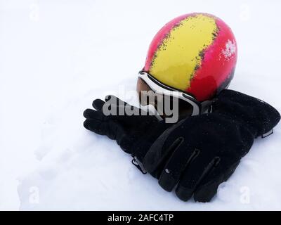 Rote und gelbe Ski Helm, weiße und schwarze Skibrille ski Handschuhe auf Schnee. Winter skifahren Thema Stockfoto