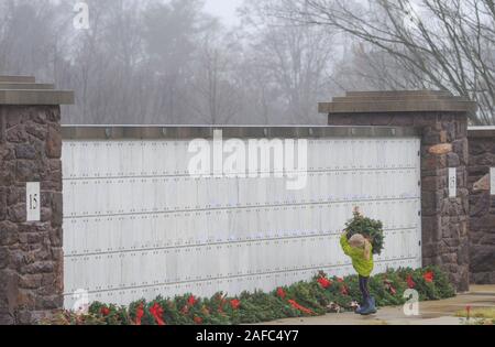 Newtown, United States. 14 Dez, 2019. Ein junges Mädchen trägt Kranzniederlegung am Grab während Kränze über Amerika Samstag, 14. Dezember 2019 in Washington Crossing National Cemetery in Newtown, Pennsylvania platziert werden. Tausende von Kränze werden jedes Jahr für Kränze über Amerika von Freiwilligen, die sammeln und dann die Kränze an den Gräbern der Veteranen getroffen werden. (Credit: William Thomas Kain/Alamy leben Nachrichten Stockfoto