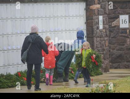 Newtown, United States. 14 Dez, 2019. Ein junges Mädchen trägt Kranzniederlegung am Grab während Kränze über Amerika Samstag, 14. Dezember 2019 in Washington Crossing National Cemetery in Newtown, Pennsylvania platziert werden. Tausende von Kränze werden jedes Jahr für Kränze über Amerika von Freiwilligen, die sammeln und dann die Kränze an den Gräbern der Veteranen getroffen werden. (Credit: William Thomas Kain/Alamy leben Nachrichten Stockfoto