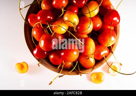 Frische süße reife Kirschen in einer Holzschale isoliert auf weißem Grund. Draufsicht. Stockfoto