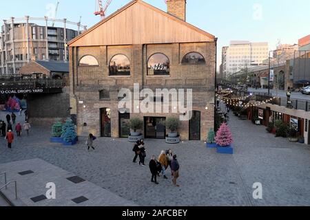 Kohle Tropfen Yard Gebäude und Besucher vorbei gehen. Weihnachtsbäume von Wolf & Badger Store im Kings Cross in London England UK KATHY DEWITT Stockfoto