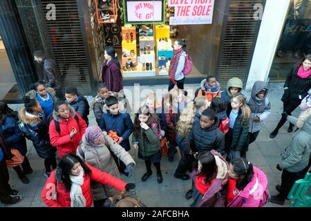 Gruppe von britischen Schulkindern und Lehrer warten auf einen Bus auf einem Einzelhandelsbesuch Städtetrip zur Oxford Street in London England Großbritannien KATHY DEWITT Stockfoto