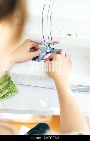 Weibliche Hände nähen weißen Stoff auf professionelle Fertigung Maschine am Arbeitsplatz Stockfoto