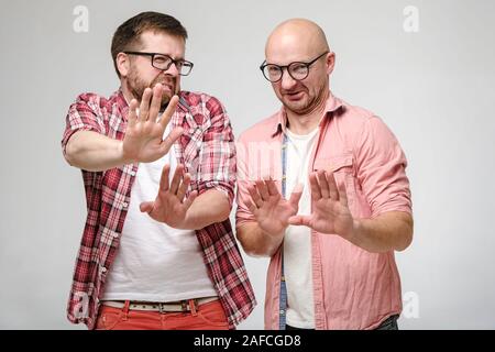 Freunden schauen in die Kamera im Ekel und verteidigen sich von vorne macht eine Geste von Palm. Negative Emotionen. Stockfoto