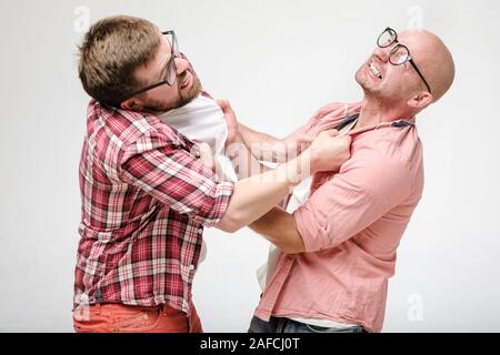 Konflikt der Freunde. Zwei Männer mit Brille geltend zu kämpfen, Sie scharf gehalten auf der Kleidung und grinste. Stockfoto