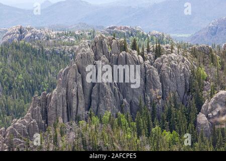 Die Aussicht von Black Elk Peak, früher genannt Harney Peak, mit Quarz Felsformationen ragt aus einem Wald Landschaft und die Berge in der Ferne in Sout Stockfoto