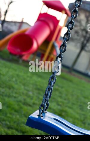 Kinderspielplatz im Gras mit blauen Schwingen und rote Folie Stockfoto