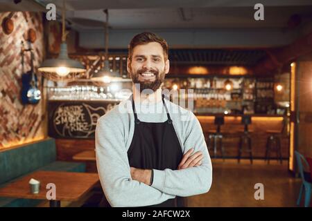 Bärtige lächelnd Barkeeper, Kellner, die auf dem Hintergrund einer Bar. Stockfoto