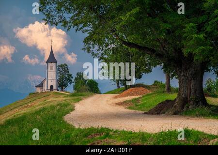 Eine atemberaubende Landschaft mit niedlichen Kirche auf dem Hügel. Spektakuläre Landschaft und fantastische charmante Saint Primoz Kirche mit Bergen im Hintergrund, Jamnik Stockfoto