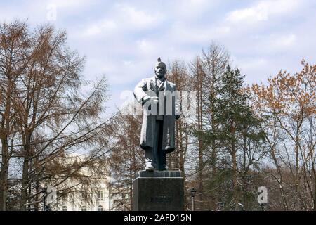 Perm, Russland - Dezember 14, 2019: Schnee bedeckt Denkmal für Wladimir Lenin mit einer auf dem Kopf im Park Taube vor dem Hintergrund der Winter Bäume Stockfoto