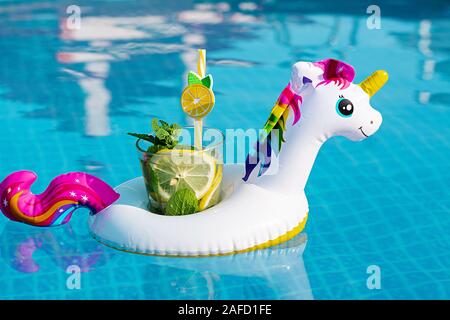 Frischen cocktail Mojito auf aufblasbaren White unicorn Toy am Pool. Ferienhäuser Konzept. Stockfoto