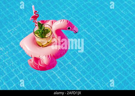 Frischen cocktail Mojito auf aufblasbaren rosa Flamingo Spielzeug am Pool. Ferienhäuser Konzept. Stockfoto