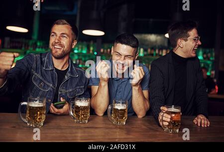 Spaß haben. Freunde in der Kneipe mit Alkohol ruht in den Händen Stockfoto