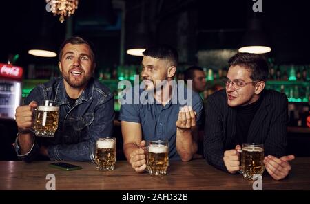 Spaß haben. Freunde in der Kneipe mit Alkohol ruht in den Händen Stockfoto