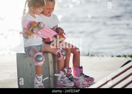 Zwei kleine Mädchen mit Rollschuhen im Freien in der Nähe der See im Hintergrund Stockfoto