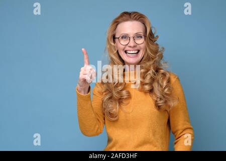 Frau in Gläsern und gelben Pullover, Zeigefinger, Ratschläge zu erteilen. Stockfoto