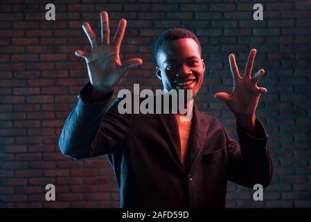 Spaß haben. Futuristische Neon Beleuchtung. Junge afrikanische amerikanische Mann im Studio Stockfoto