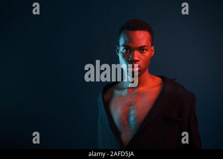 Zuversichtlich und ernst. Futuristische Neon Beleuchtung. Junge afrikanische amerikanische Mann im Studio Stockfoto