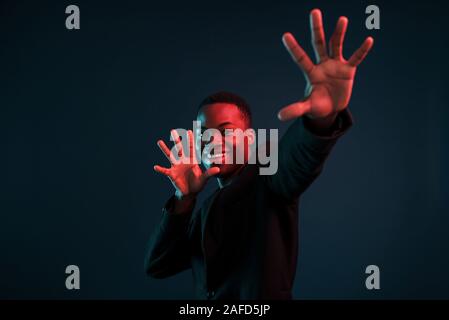 Spaß haben. Futuristische Neon Beleuchtung. Junge afrikanische amerikanische Mann im Studio Stockfoto