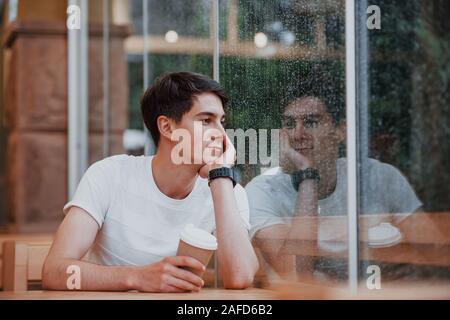 Portrait von jungen Studenten, die im Café zu regnerischen Tag sitzt. Eine Person Stockfoto