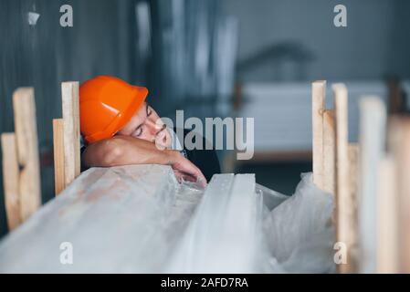 Schlafen auf einen Job. Eine Pause. Industrielle Arbeiter drinnen im Werk. Junge Techniker mit orange Schutzhelm Stockfoto