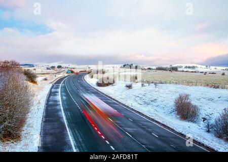 Tabay, Cumbria, Großbritannien. 15. Dezember, 2019. Dezenten Farbtönen in der Morgendämmerung; am frühen Morgen Frost und Schnee Duschen für die tabay Winterlandschaft als Verkehr Köpfe für Shap ein renommierter kalten schwierigen Fahrsituationen Punkt im Allgäu Hochmoore. Credit: MediaWorldImages/Alamy leben Nachrichten Stockfoto