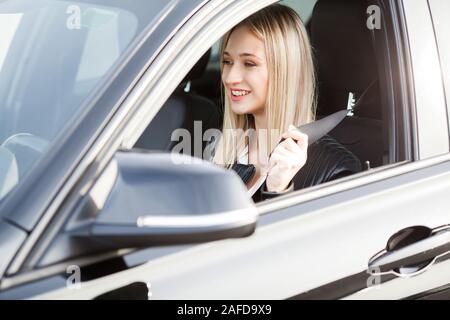 Elegante business Frau, die in der Klage zur Befestigung der sicheren Riemen vor seinem Auto fährt gekleidet Stockfoto