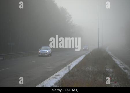 Autos im Nebel. Schlechtes Wetter und gefährlichen Autoverkehr auf der Straße. Light Vehicles in nebligen Tag. Stockfoto