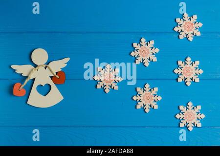 Holz- Weihnachten figuren von Engel und Schneeflocken werden auf einem blauen Hintergrund Stockfoto