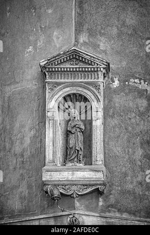 Ein grungy Bearbeiten einer kleinen Statue Nische der Jungfrau Maria mit dem Jesuskind an der Ecke eines Gebäudes in Rom, Italien Stockfoto